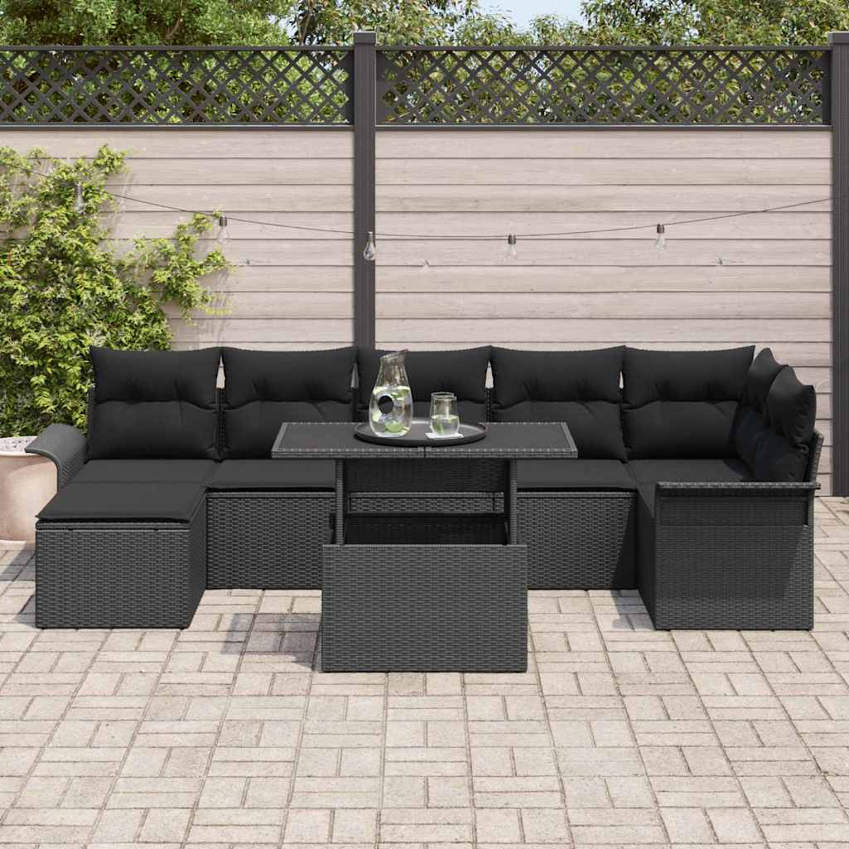 Schwarzes Ecksofa im Freien mit Kissen und einem Tisch. Ein Glas Wasser auf einem Tablett. Der Hintergrund ist ein Holzzaun.