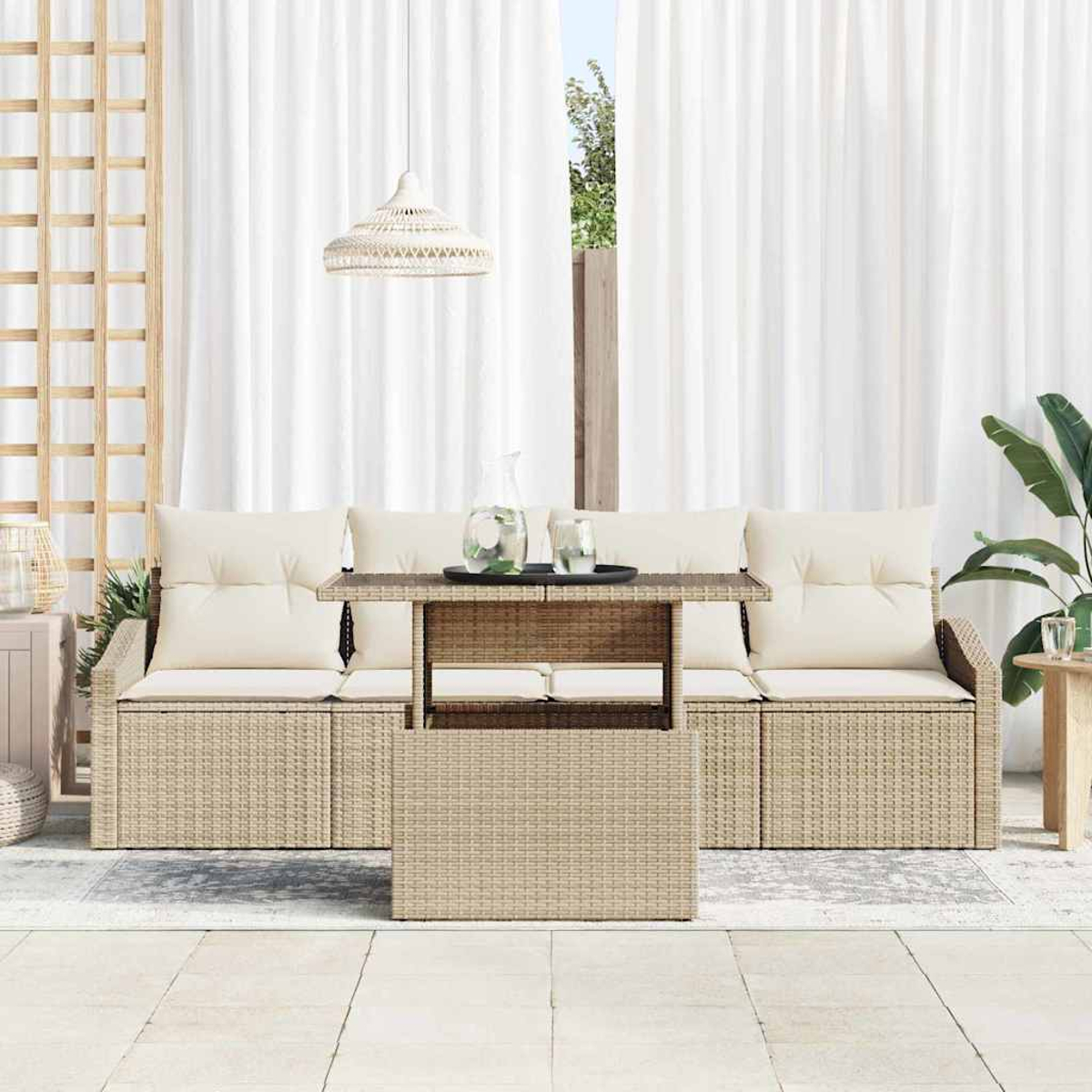 Outdoor-Rattansofa-Set mit cremefarbenen Kissen, einem Tisch mit Getränken und weißen Vorhängen im Hintergrund.