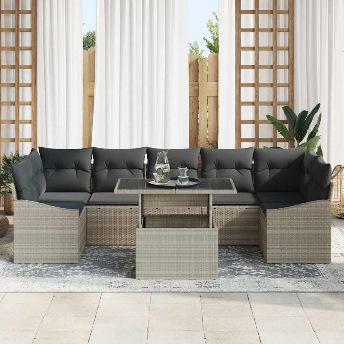 Outdoor-Ecksofa mit grauen Kissen, Glastisch mit Getränken und weißen Vorhängen im Hintergrund.