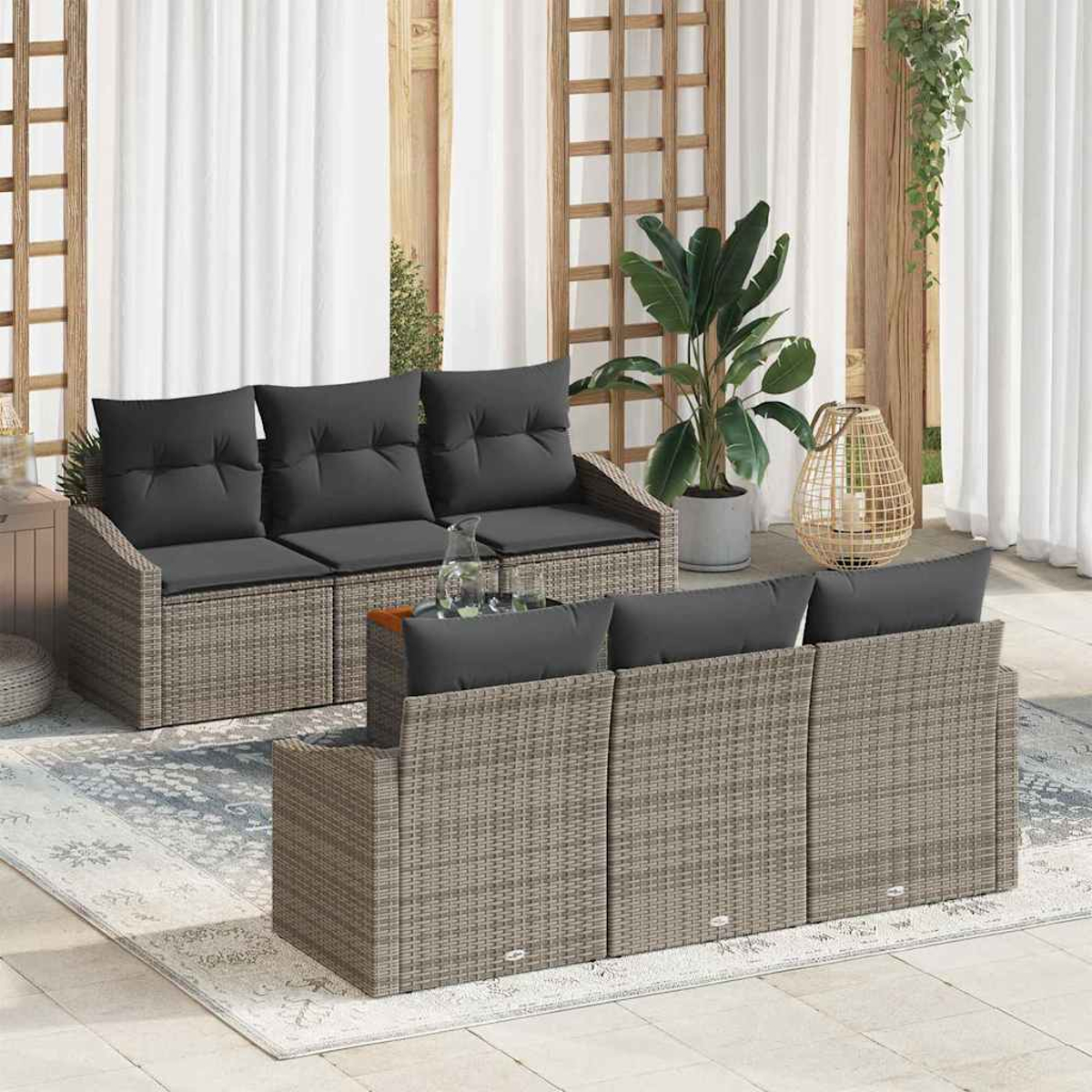 Garten-Terrassenset mit grauen Kissen und Korbflechtrahmen. Enthält zwei Sofas, einen Teppich, Pflanzen und eine dekorative Laterne. Weiße Vorhänge.