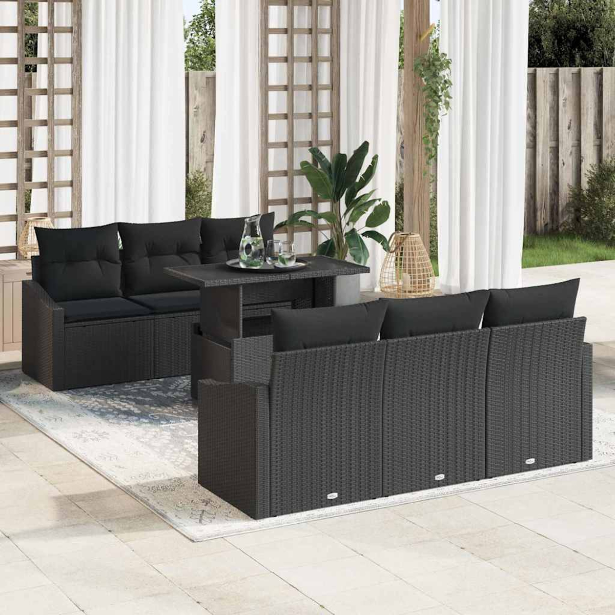 Outdoor-Set aus schwarzem Korbgeflecht mit Kissen, Tisch, Teppich, Vorhängen und Pflanzen auf einer Terrasse. Enthält ein Sofa und Stühle.