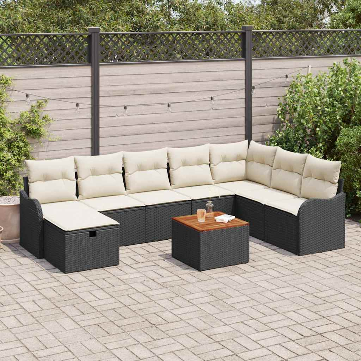 Sofá seccional al aire libre con cojines crema y una mesa de centro de madera en un patio. Jardín con valla y vegetación.