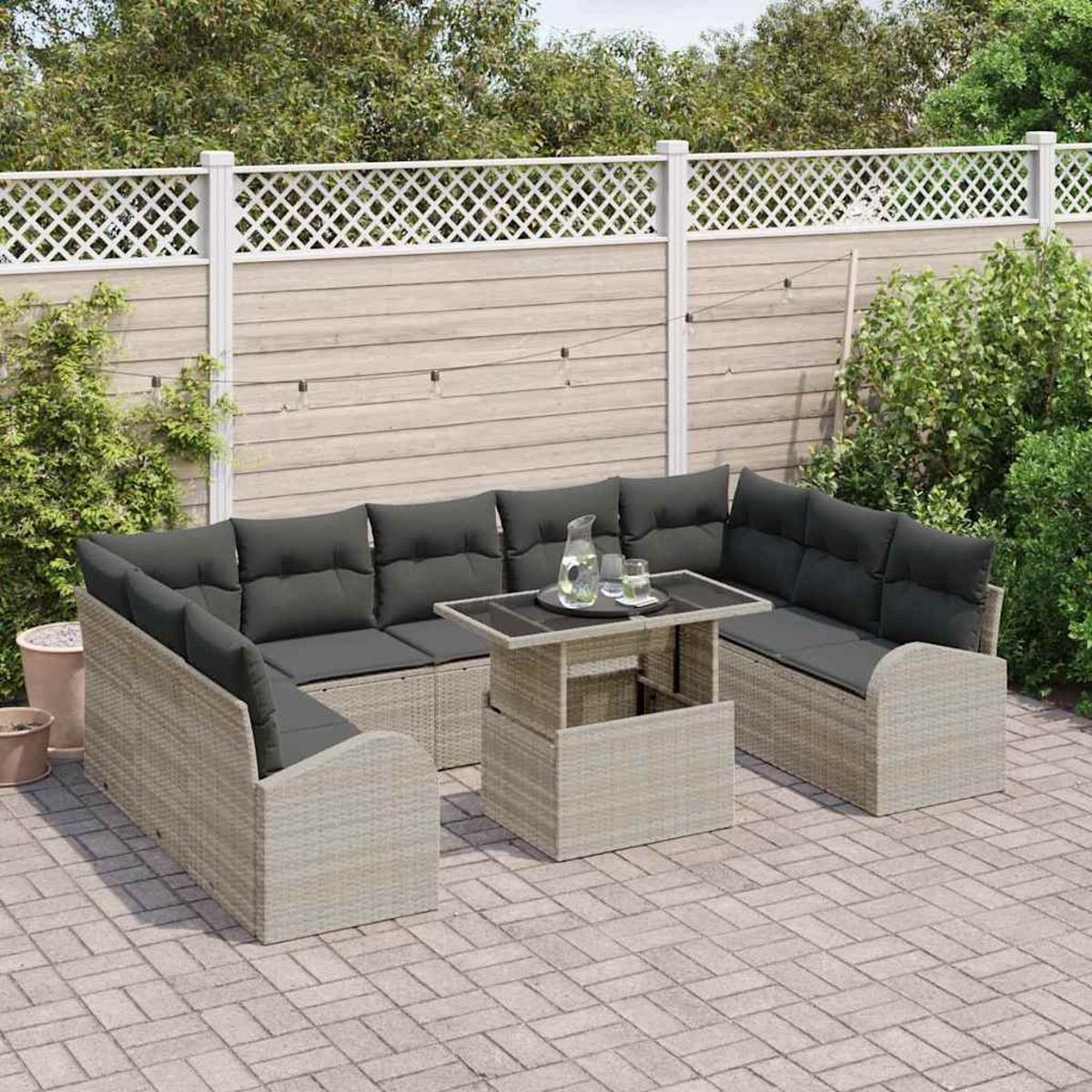 Garten-Set mit grauen Kissen, Tisch mit Glaskrug und weißem Zaun im Hintergrund.