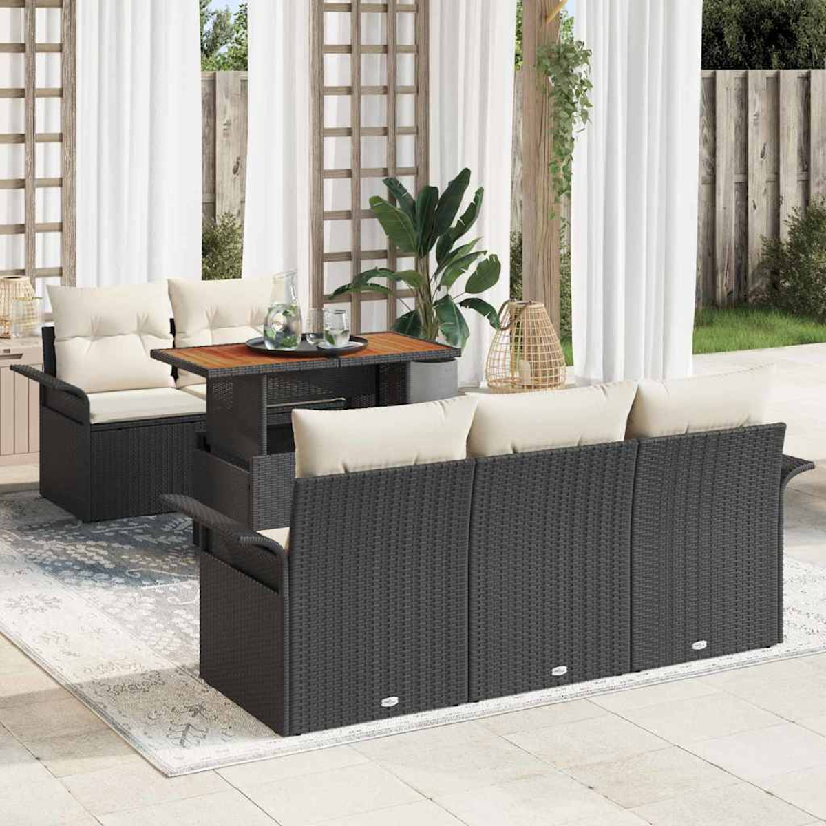 Garten-Terrassenset mit dunklen Korbmöbeln, cremefarbenen Kissen, Holztisch und durchsichtigen weißen Vorhängen im Hintergrund.