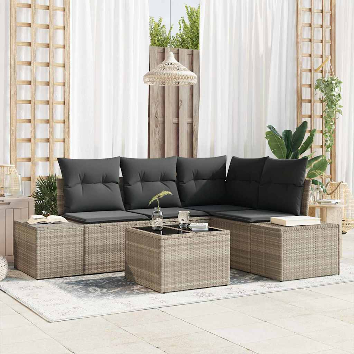 Garten-Ecksofa aus Korbgeflecht mit dunklen Kissen und einem Couchtisch mit Glasplatte auf einem hell gemusterten Teppich.