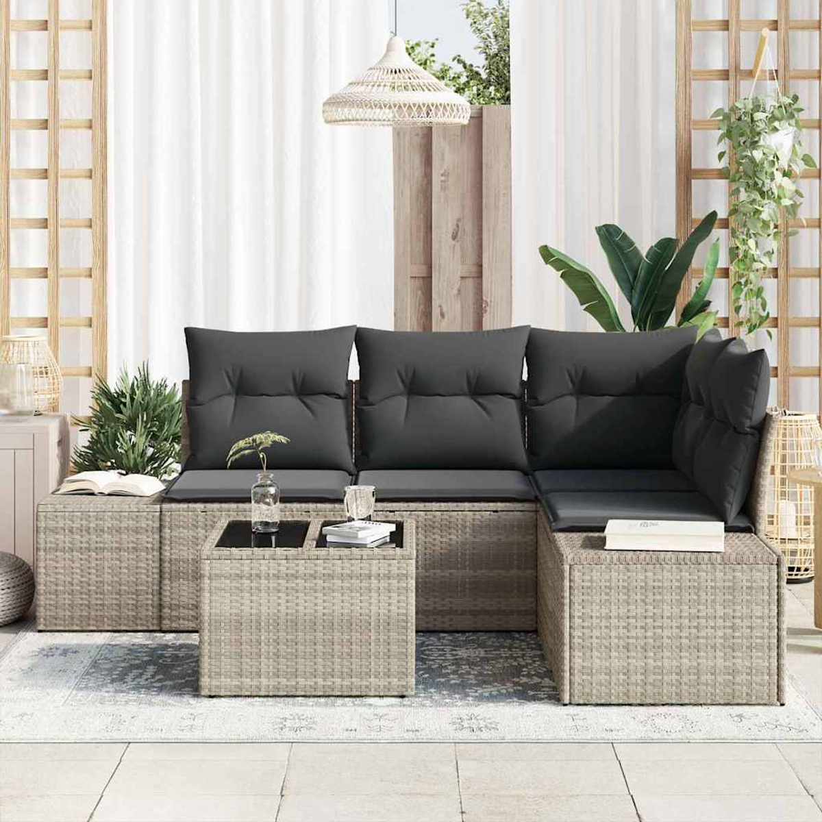 Outdoor-Sitzbereich mit grauen Kissen, einem schwarzen Tisch und Pflanzen. Die Szene umfasst weiße Vorhänge und eine gewebte Lampe.