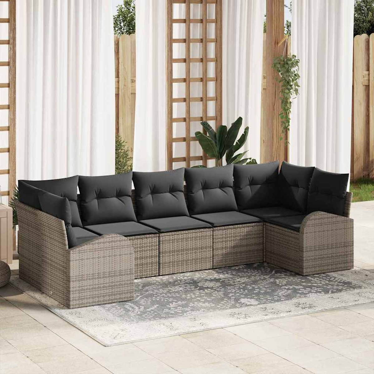Gartenecksofa mit grauen Kissen, auf einem gemusterten Teppich in einer Hinterhofumgebung.