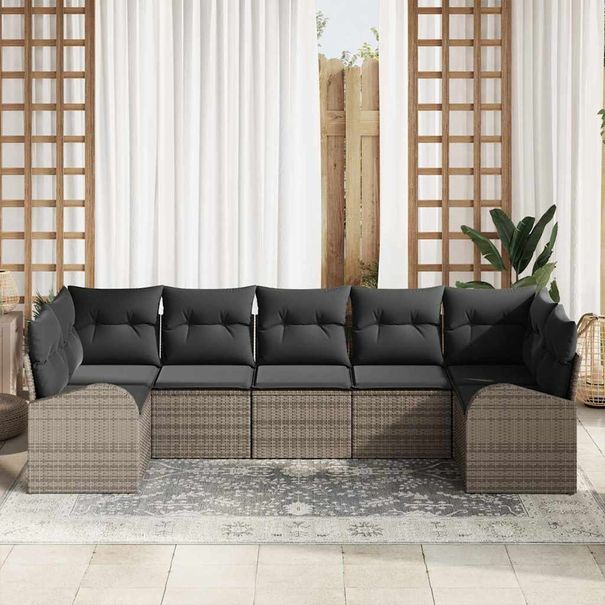 Outdoor-Ecksofa mit grauen Kissen. Dahinter weiße Vorhänge, Holzgitter und ein Hauch von Grün.