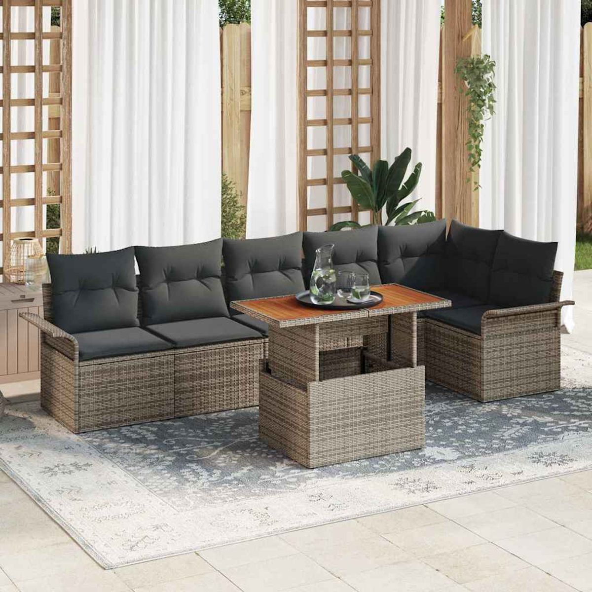 Gartenmöbel-Set mit grauen Kissen, einem Couchtisch und einem Teppich auf einer Terrasse. Weiße Vorhänge und ein Holzgitter im Hintergrund.