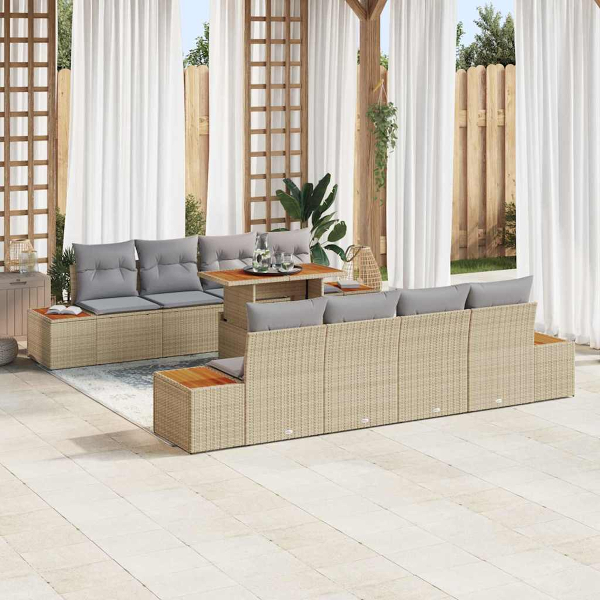 Terrassenset mit beigen Korbmöbeln, grauen Kissen und einem Holztisch. Weiße Vorhänge und ein Holzzaun sind im Hintergrund.