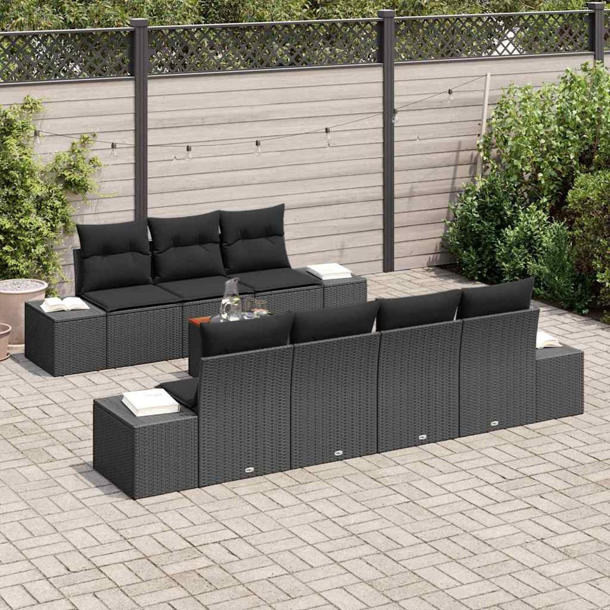 Juego de patio al aire libre con cojines negros y mimbre gris. Incluye dos sofás y mesas auxiliares. Escenario de patio trasero con valla y vegetación.
