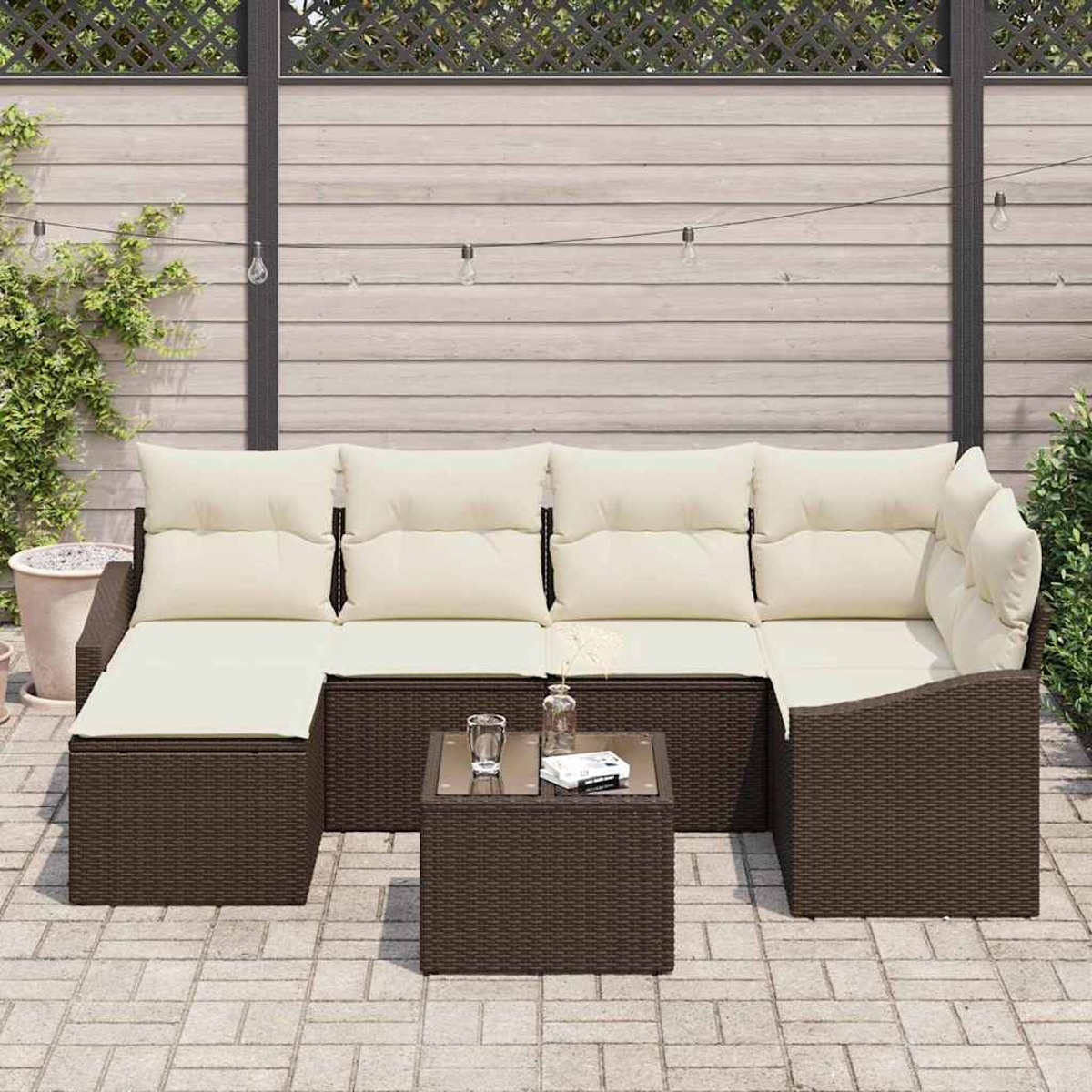 Outdoor-Ecksofa mit cremefarbenen Kissen und einem kleinen Tisch. Die Szene zeigt eine Ziegelterrasse und einen Holzzaun.