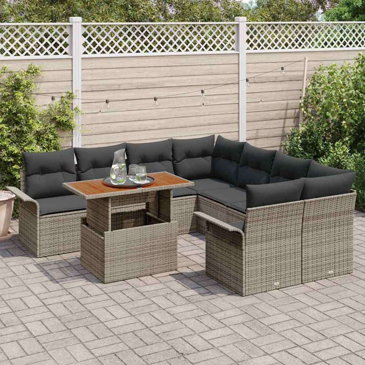 Outdoor-Ecksofa mit dunklen Kissen und einem Aufsatztisch. Im Hintergrund ein Zaun und Grün.