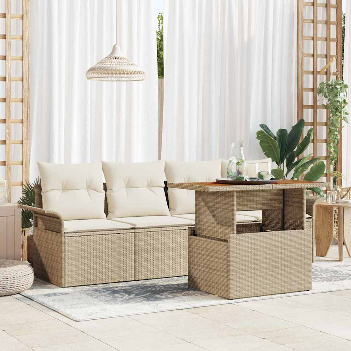 Outdoor-Setting mit einem Korbmöbel-Sofa und -Tisch. Weiße Vorhänge im Hintergrund, eine Hängelampe und Pflanzen vervollständigen die Szene.