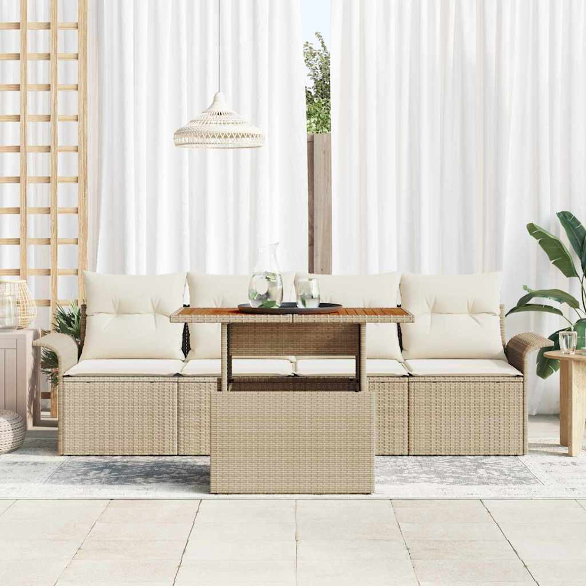 Outdoor-Sitzbereich mit einem Korbtisch, Kissen und weißen Vorhängen. Auf dem Tisch stehen eine Wasserkaraffe und Gläser.