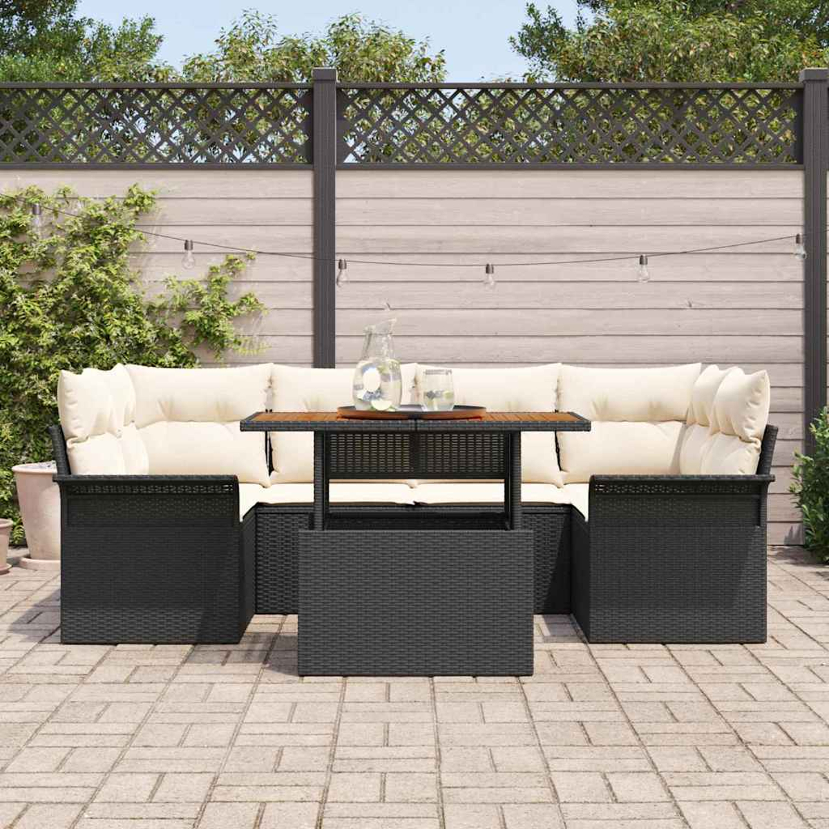 Garten-Sitzgruppe mit schwarzem Korbgeflecht, cremefarbenen Kissen und einem Holztisch. Sie steht auf einer Terrasse, mit einem Holzzaun im Hintergrund.