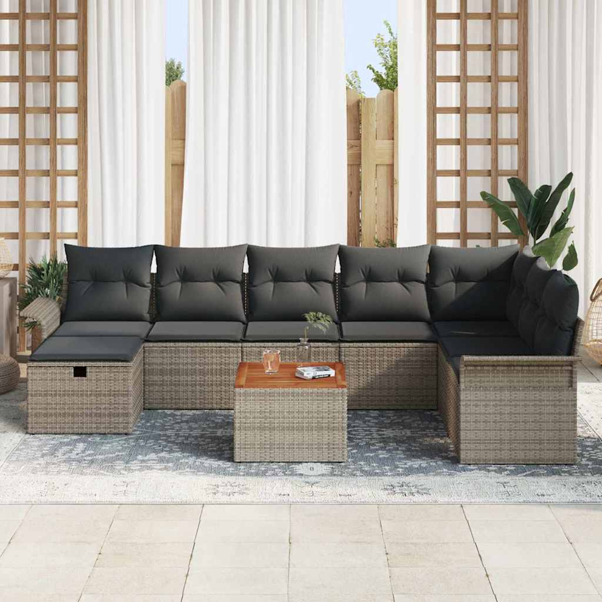 Outdoor-Ecksofa mit grauen Kissen und einem Holztisch. Weiße Vorhänge und ein Spalier befinden sich im Hintergrund.