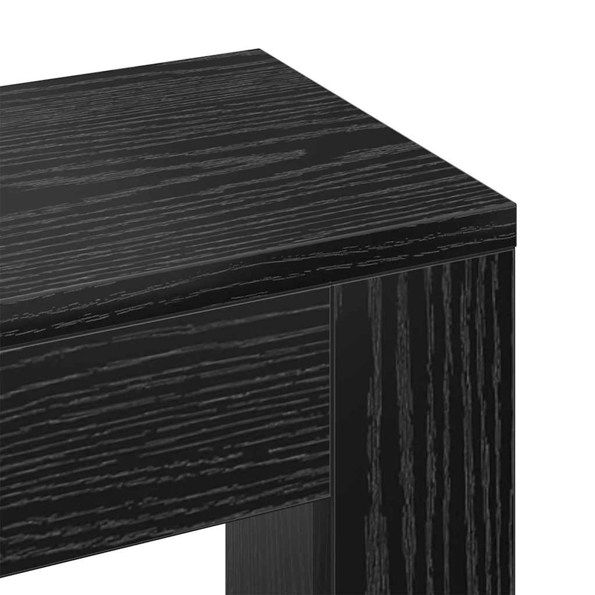 Nahaufnahme einer schwarzen Holztischecke. Die Holzmaserung ist sichtbar. Die Tischkante und ein Bein sind im Bild.