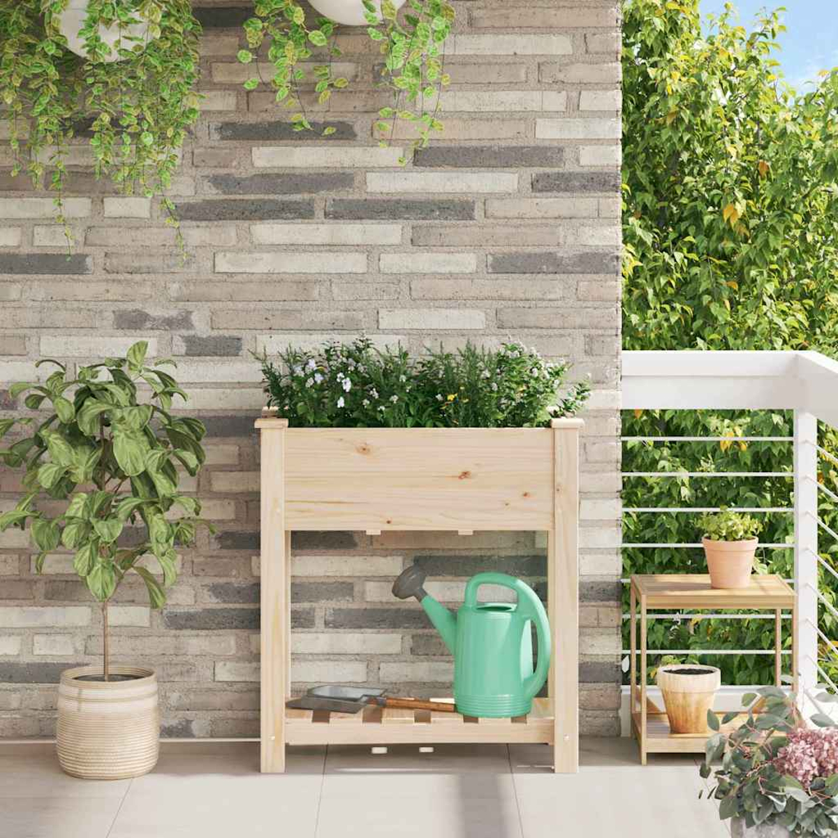 Una fioriera in legno con piante, un annaffiatoio verde e un tavolino con una pianta in vaso su un balcone con un muro di mattoni.