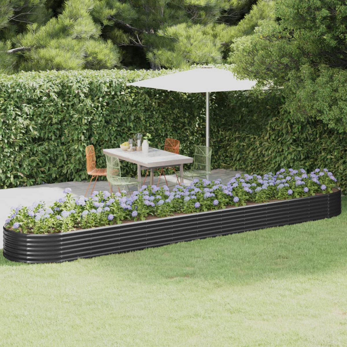 Eine Gartenszene mit Tisch, Stühlen und einem schwarzen Pflanzkasten mit blauen Blumen. Grüner Rasen und Bäume umgeben ihn.