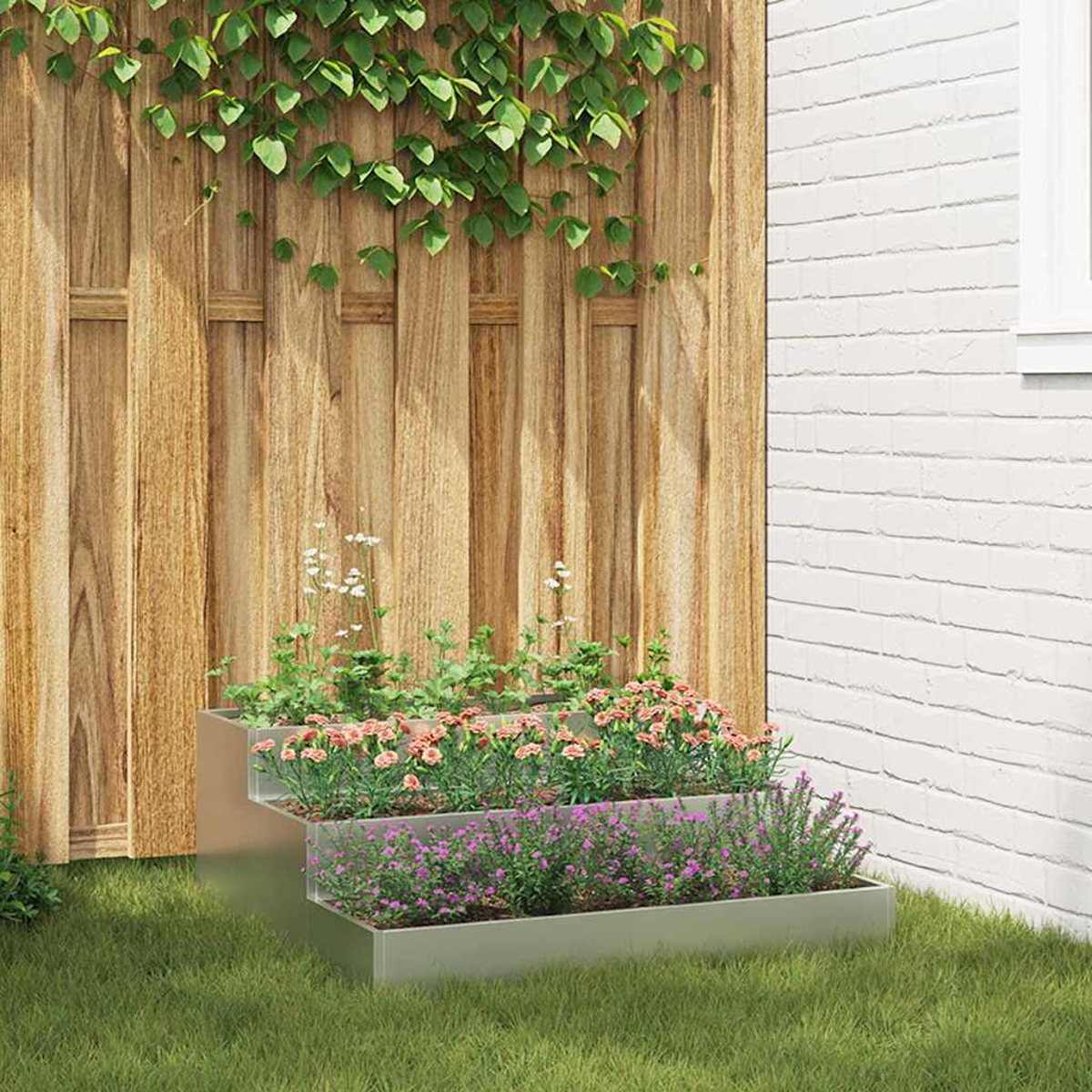 Una fioriera a più livelli con fiori rosa e viola è sull'erba. Una staccionata in legno e un muro di mattoni bianchi fanno da sfondo.