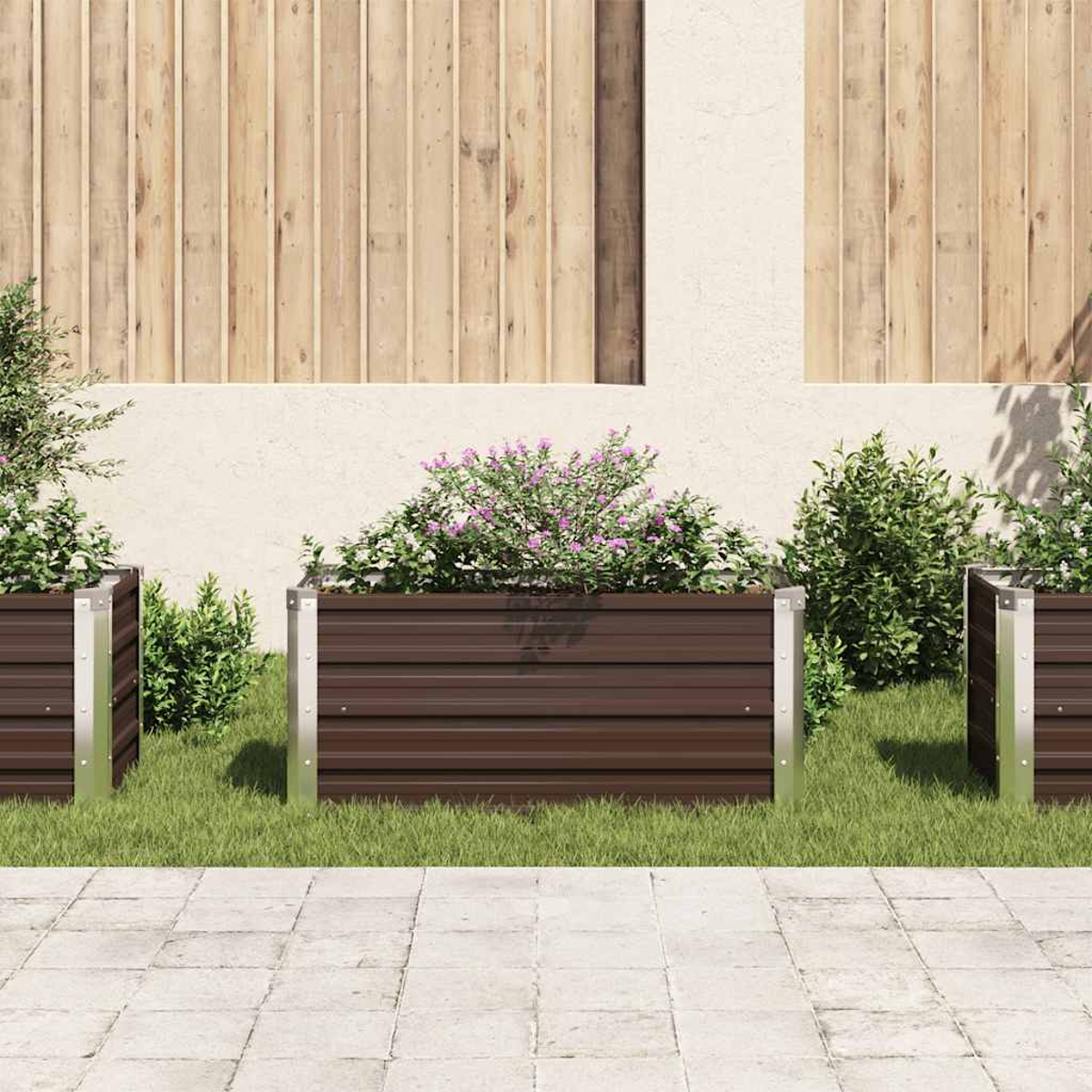 Drei braune Metallpflanzkästen mit Pflanzen und Blumen stehen auf Gras. Ein Holzzaun und eine cremefarbene Wand bilden den Hintergrund.