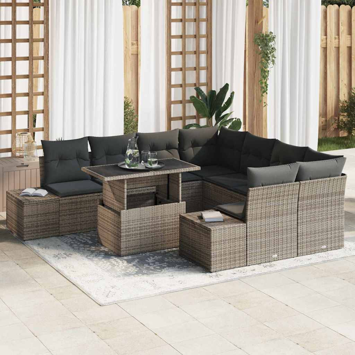 Outdoor-Wicker-Ecksofa mit schwarzen Kissen, einem Tisch mit Hebefunktion und Beistelltischen auf einem Teppich, in der Nähe weißer Vorhänge.