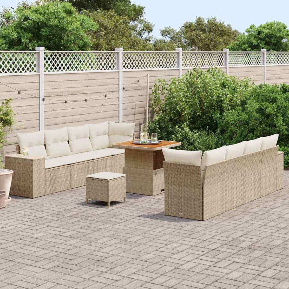 Juego de patio exterior con sofás de mimbre, mesa y otomana sobre un patio de ladrillos, rodeado de una valla de madera y vegetación.