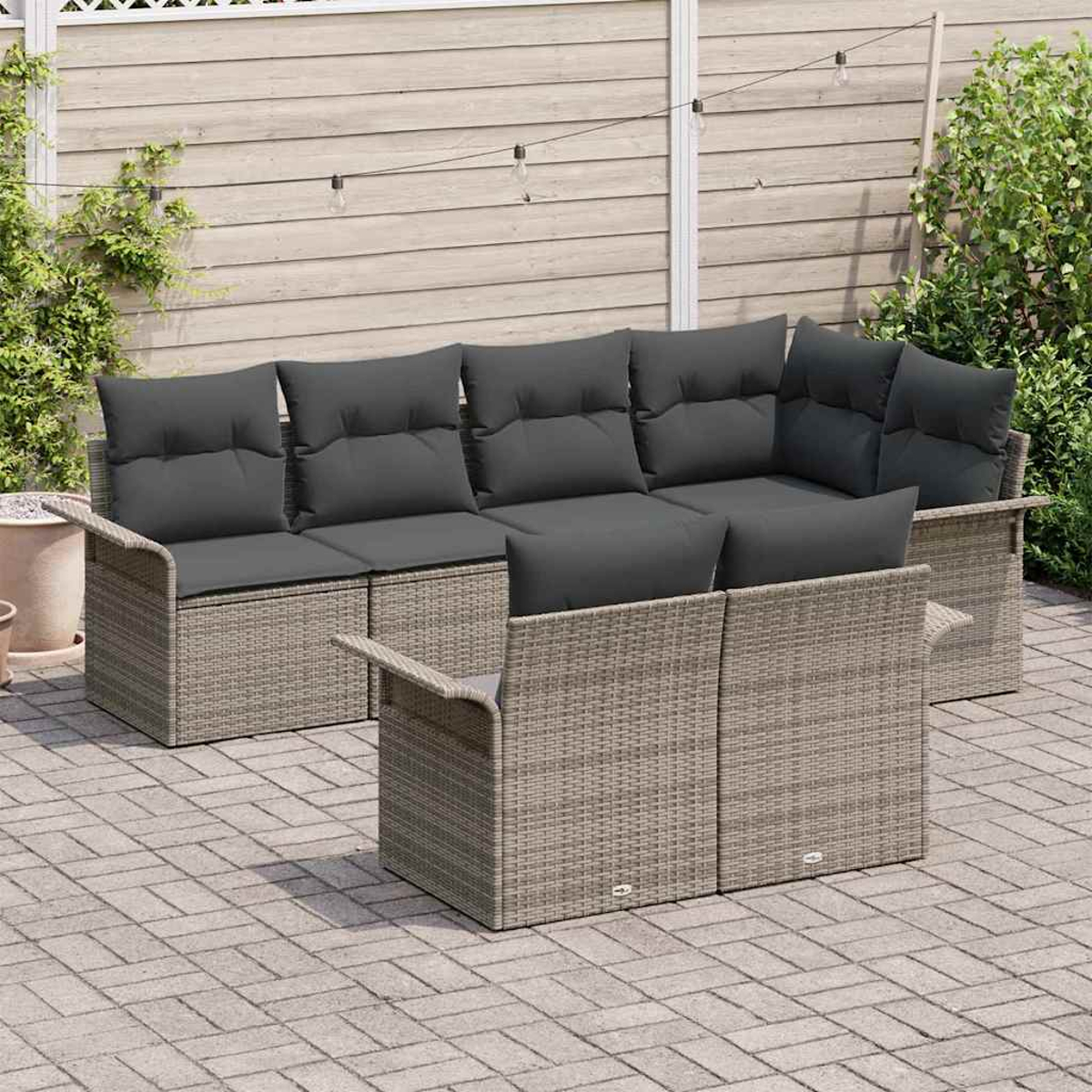 Graues Outdoor-Rattan-Sofaset mit dunkelgrauen Kissen auf einer Backstein-Terrasse, mit Holzzaun und Pflanzen im Hintergrund.
