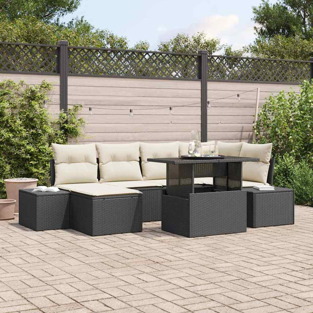 Gartenmöbel-Set mit Sofa, Ottomanen und Tisch. Beige Kissen kontrastieren mit den dunkelgrauen Möbeln. Ein Hinterhof ist sichtbar.