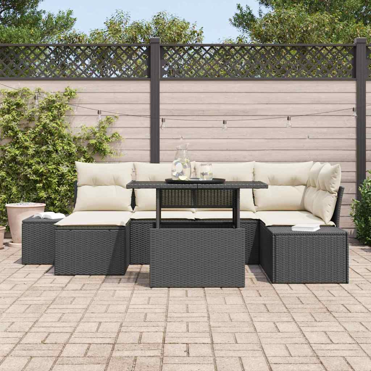Garten-Sitzgruppe mit Tisch, Kissen und Zaun im Hintergrund. Die Möbel stehen auf einer Ziegelterrasse.