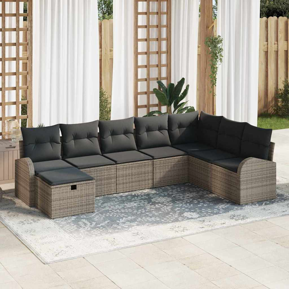 Outdoor-Ecksofa mit grauen Kissen auf einem gemusterten Teppich. Weiße Vorhänge und Holzgitter im Hintergrund. Sonnenlicht.