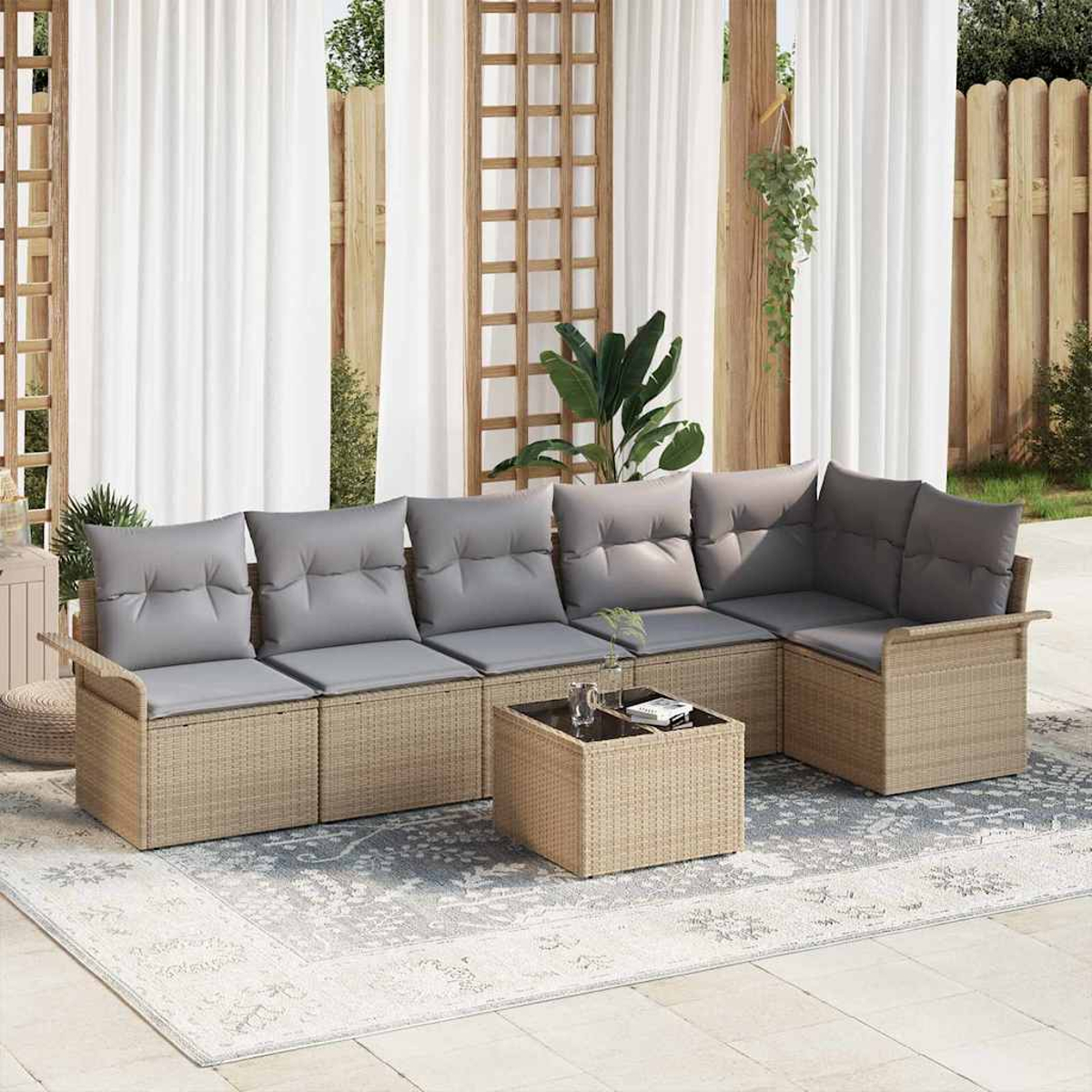 Outdoor-Ecksofa mit grauen Kissen, Korbtisch und gemustertem Teppich. Im Hintergrund Vorhänge und Holzkonstruktionen.
