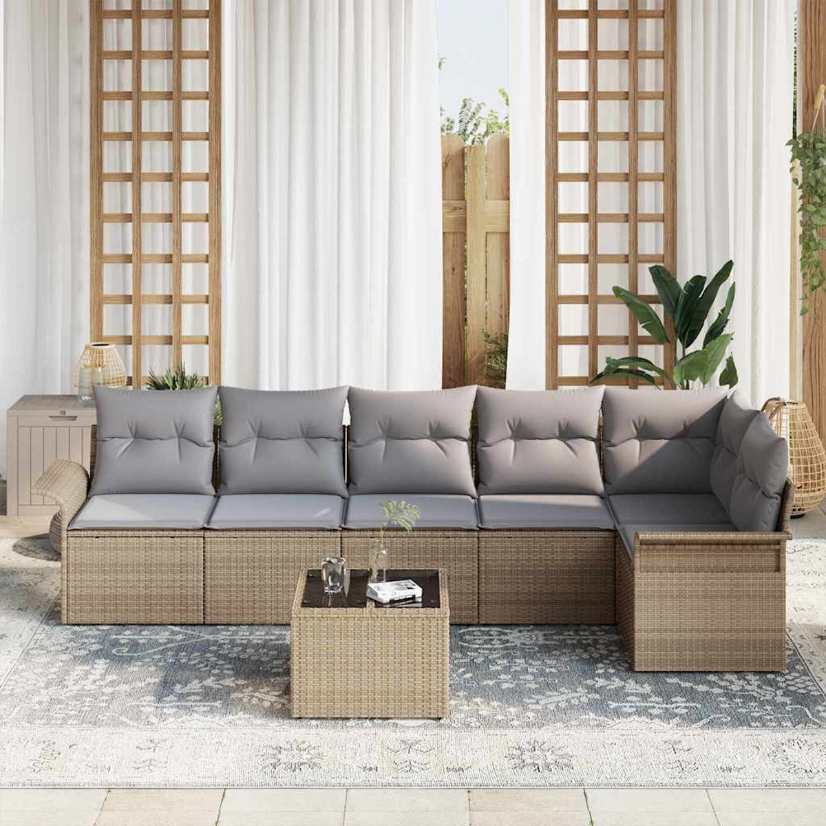 Outdoor-Ecksofa mit grauen Kissen und einem kleinen Tisch auf einem gemusterten Teppich. Hintergrund: Vorhänge und ein Holzgitter.