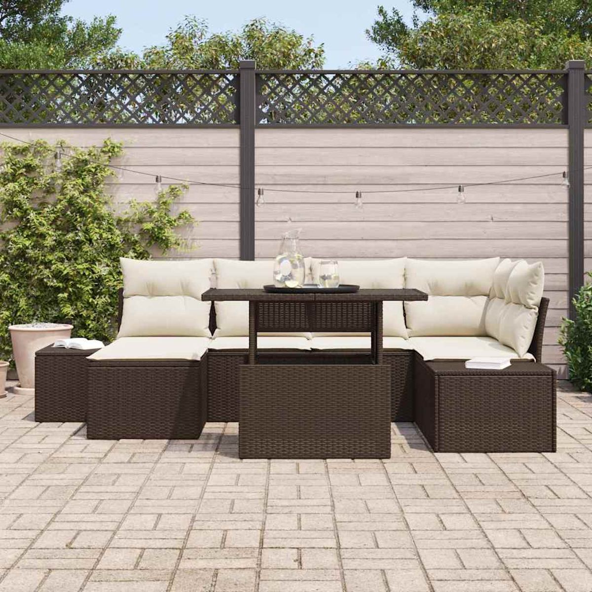 Terrassenset mit braunen Korbmöbeln, cremefarbenen Kissen und einem zentralen Tisch. Enthält einen Zaun, Pflanzen und eine Backsteinterrasse.