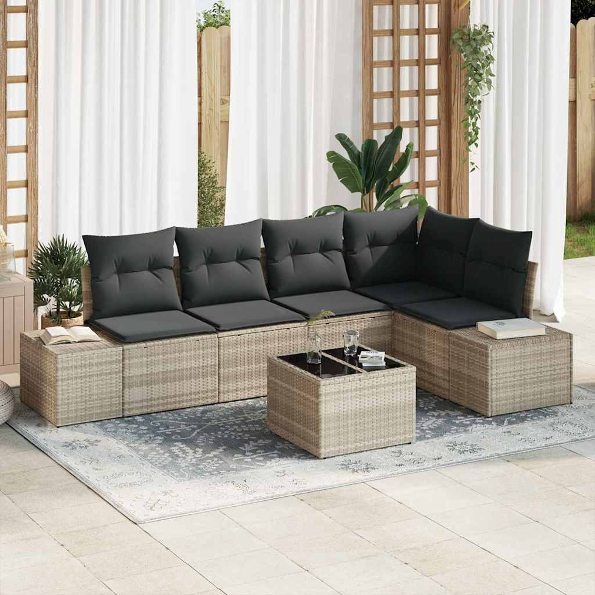Moderner Sitzbereich im Freien. Enthält ein Korasofa mit grauen Kissen, einen Couchtisch und einen gemusterten Teppich. Weiße Vorhänge im Hintergrund.