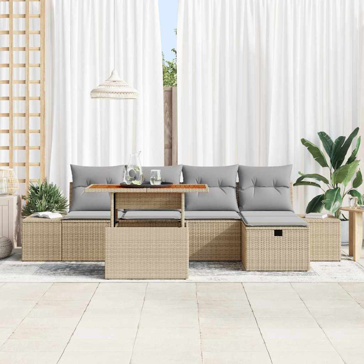 Gartenmöbel-Set aus Korbgeflecht mit grauen Kissen. Ein Holztisch trägt Wasserkrug und Gläser, vor weißem Vorhang.