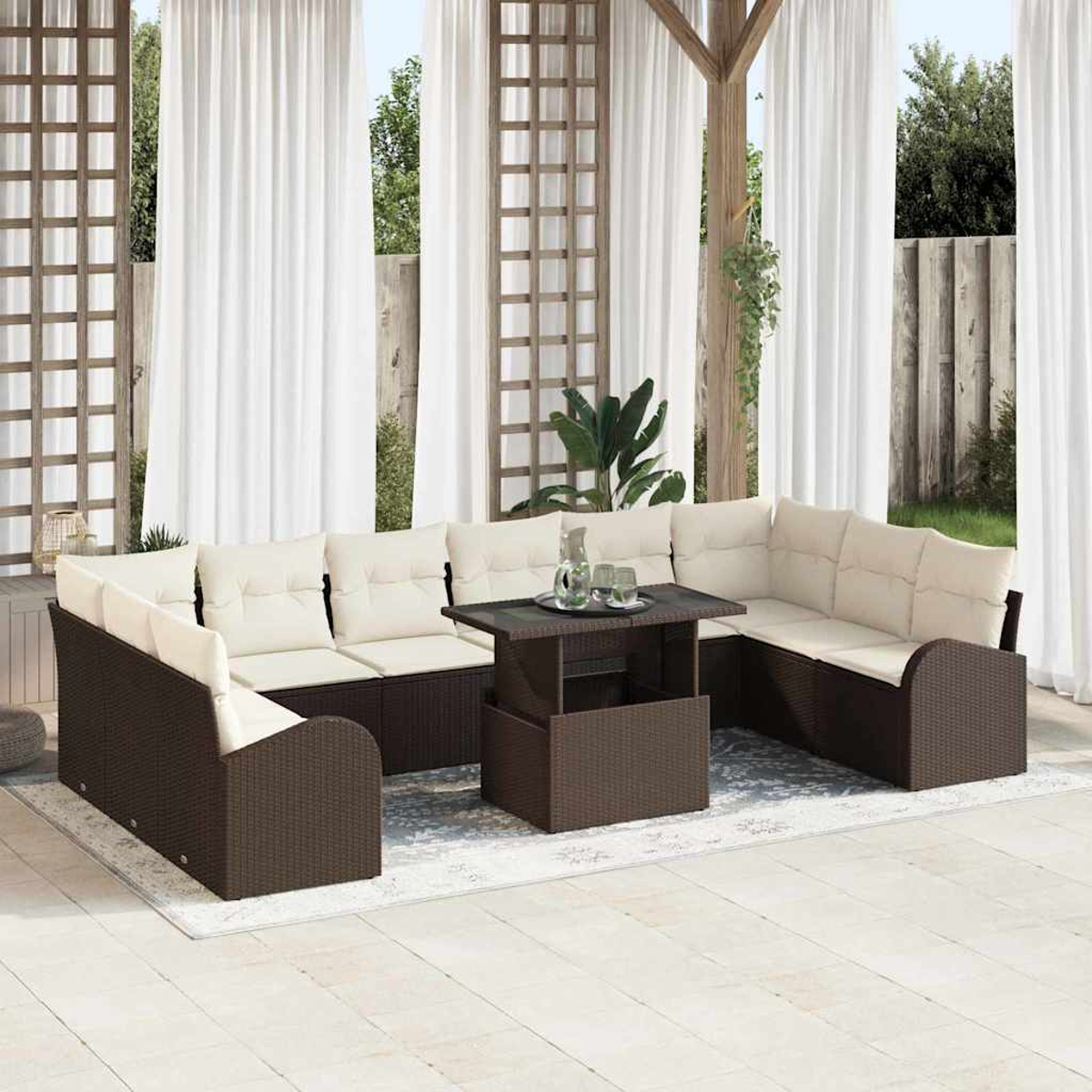 Outdoor-Terrassenset mit braunen Korbmöbeln, beigen Kissen und einem Tisch mit Hubfunktion. Weiße Vorhänge und eine Holzpergola im Hintergrund.