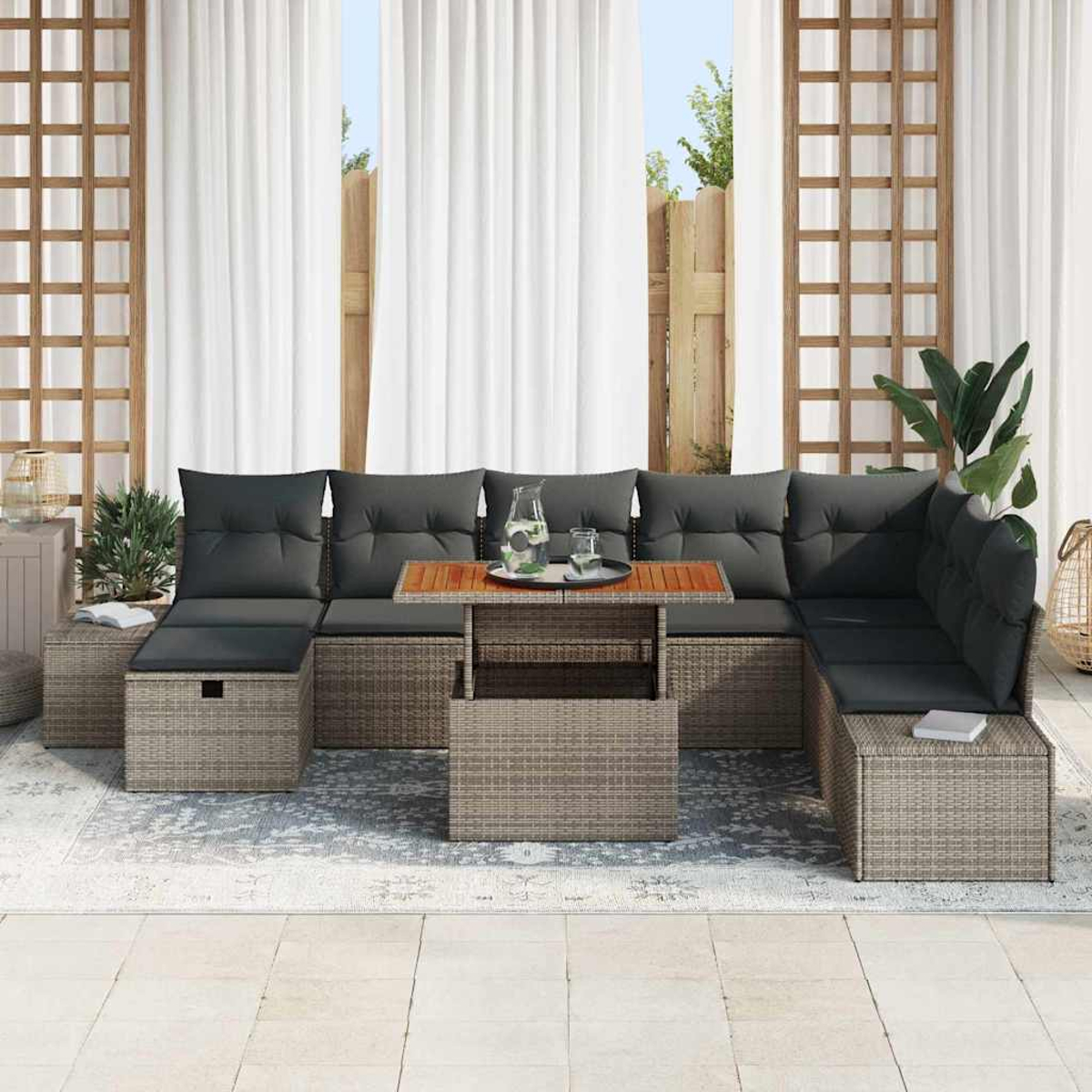Gartenmöbel mit grauen Kissen, einem Holztisch und weißen Vorhängen im Hintergrund. Ein Teppich und Pflanzen vervollständigen die Szene.