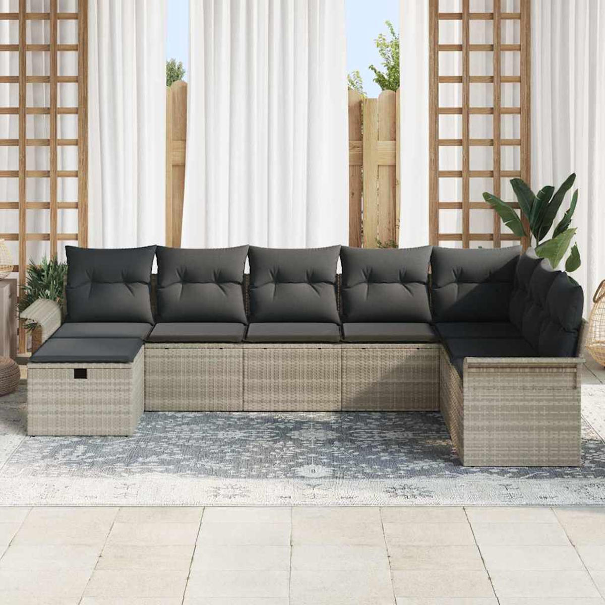 Ein graues Ecksofa für den Außenbereich mit grauen Kissen. Dahinter befinden sich weiße Vorhänge und ein Holzgitter. Der Boden ist gefliest.