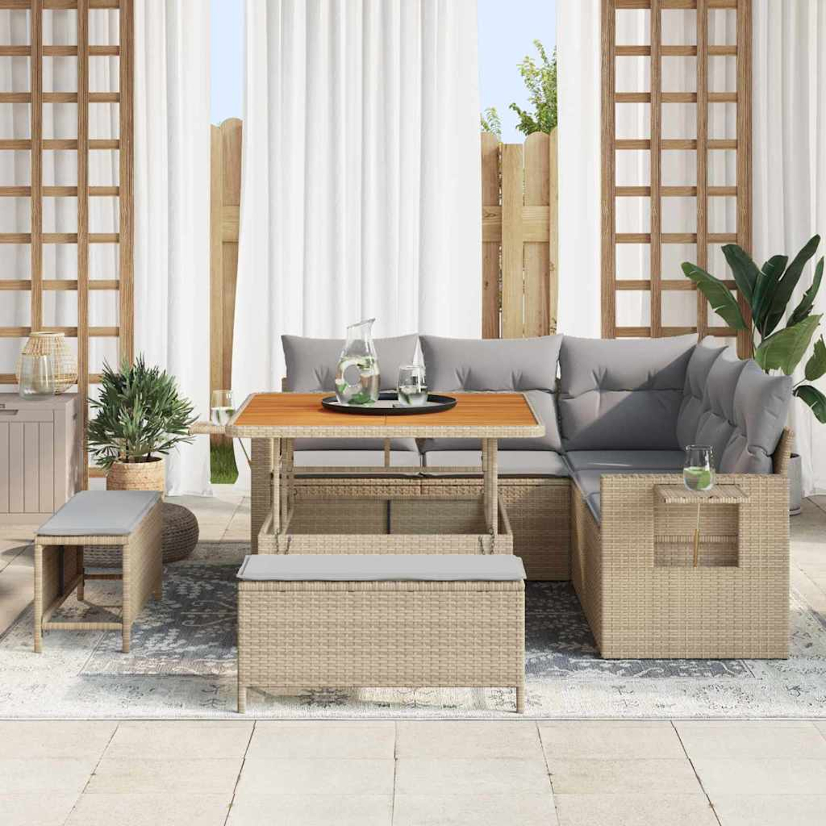 Set da patio esterno con tavolo, divano componibile e panche. Include brocca d'acqua e bicchieri. Tende bianche sullo sfondo.