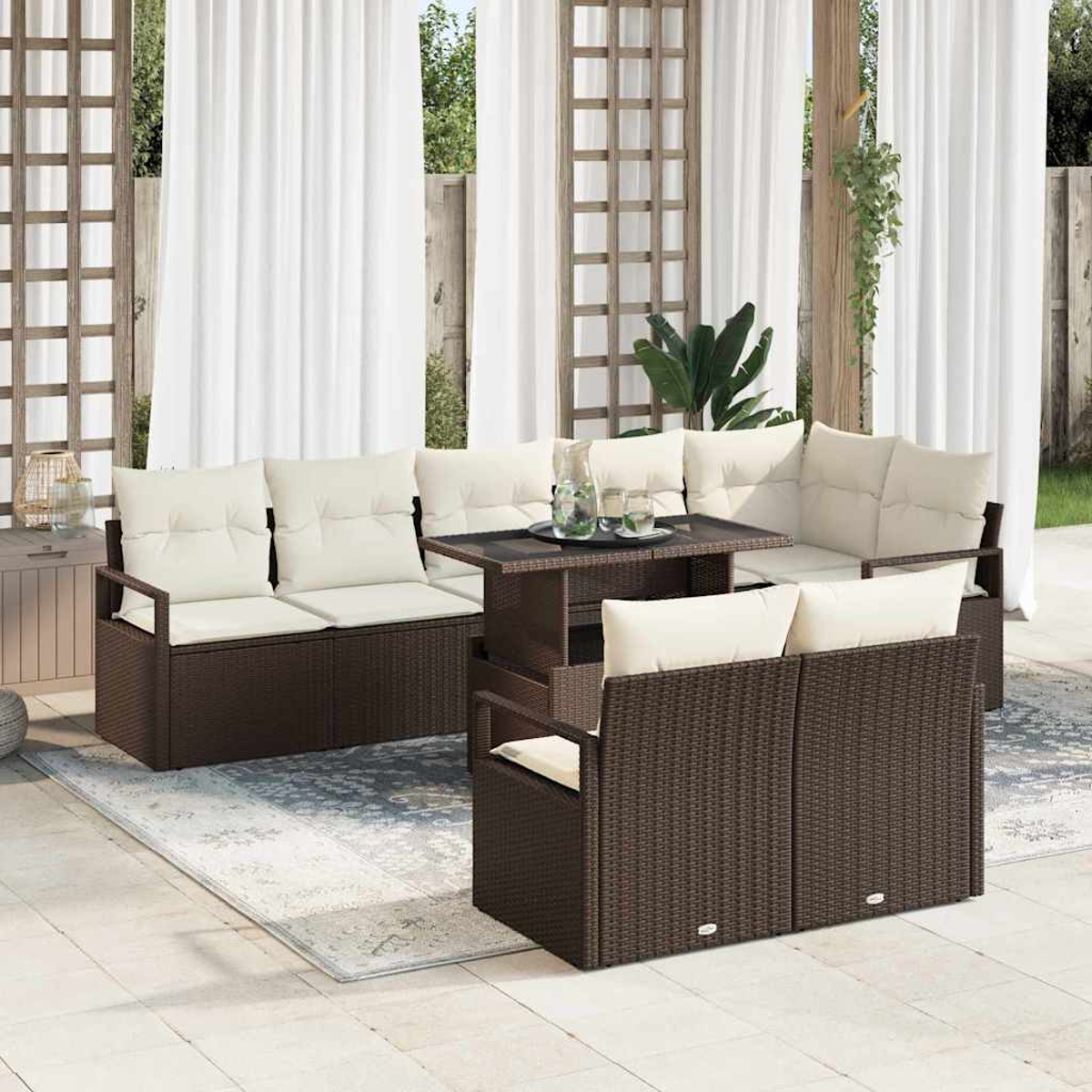 Garten-Terrassenset mit braunen Korbmöbeln, cremefarbenen Kissen und einem Tisch mit Glasplatte. Weiße Vorhänge bilden den Hintergrund.