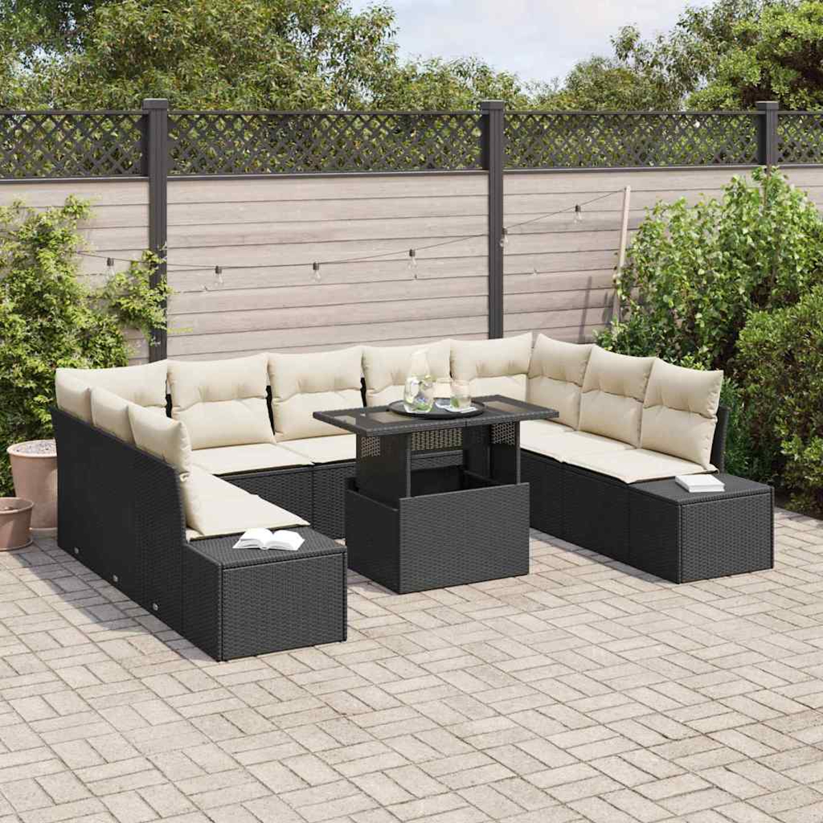 Ein schwarzes Outdoor-Ecksofa aus Rattan mit beigefarbenen Kissen, einem passenden Tisch, auf einer gepflasterten Terrasse, mit Holz