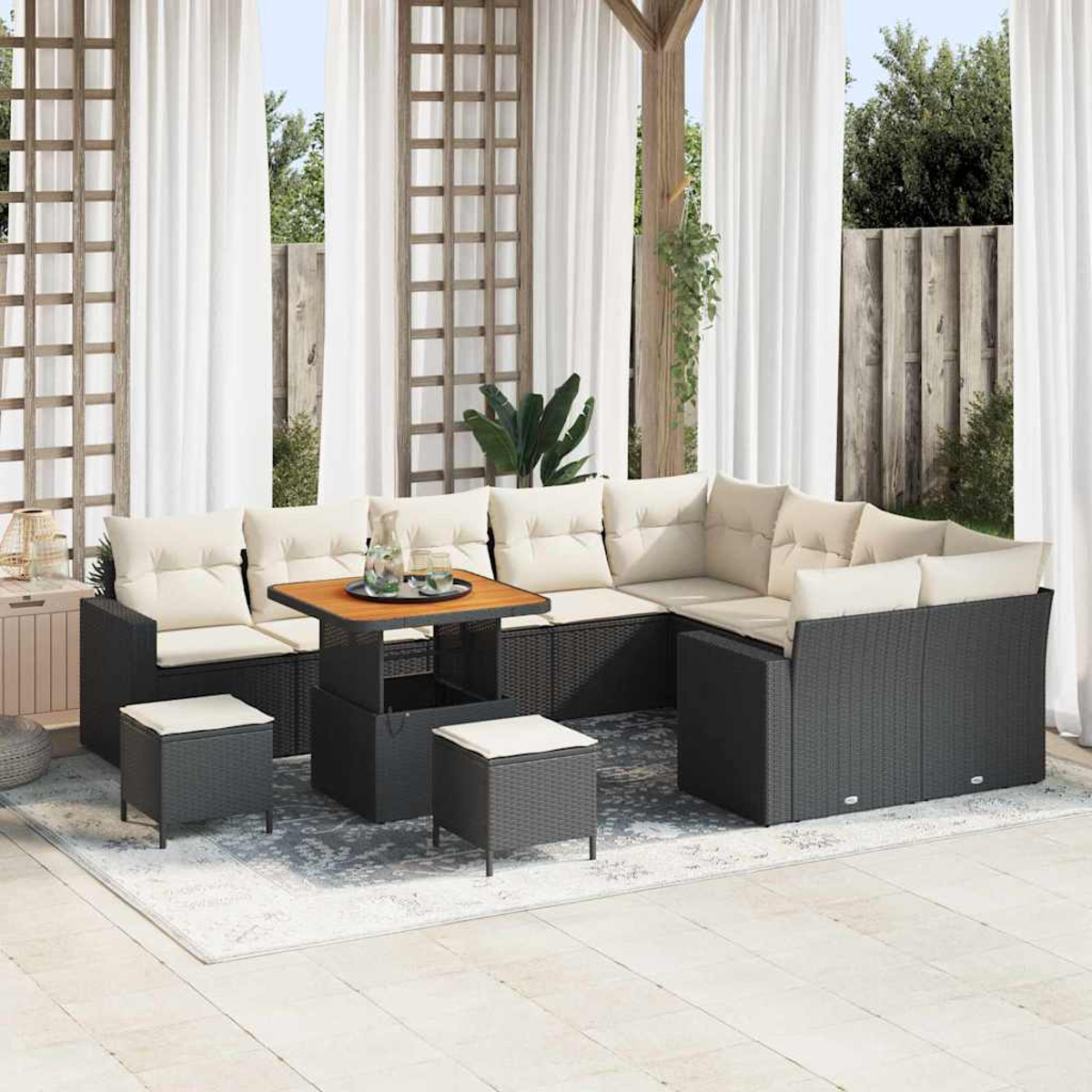 Outdoor-Ecksofa mit beigen Kissen, einem Holztisch und Hockern auf einem Teppich. Weiße Vorhänge und Holzgitter im Hintergrund.