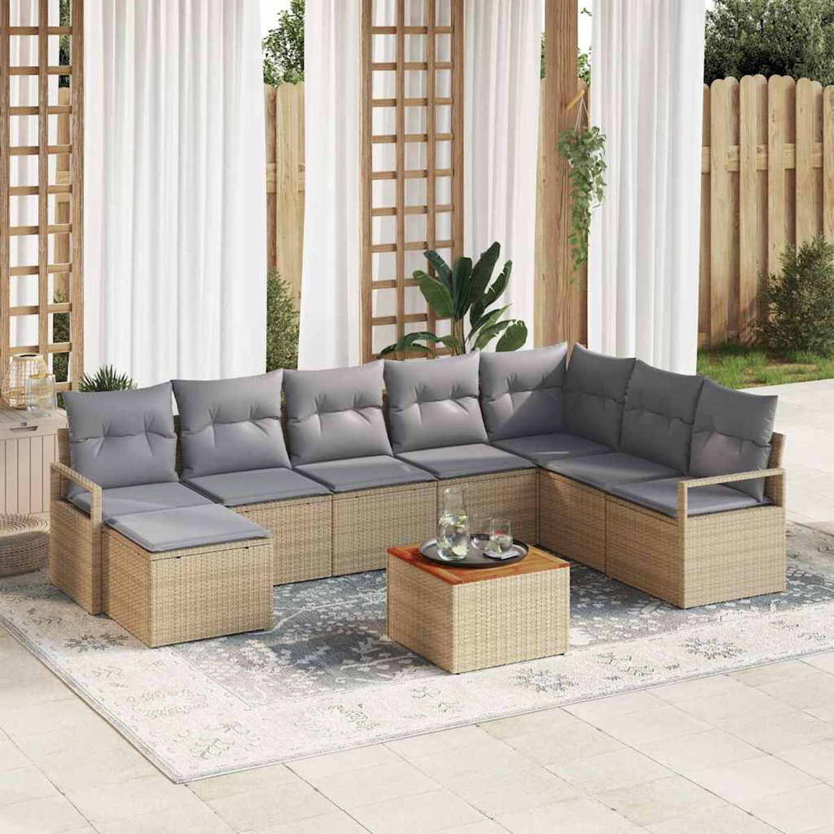 Outdoor-Ecksofa mit grauen Kissen, auf einem Teppich, mit einem Couchtisch. Weiße Vorhänge und Holzzaun im Hintergrund.
