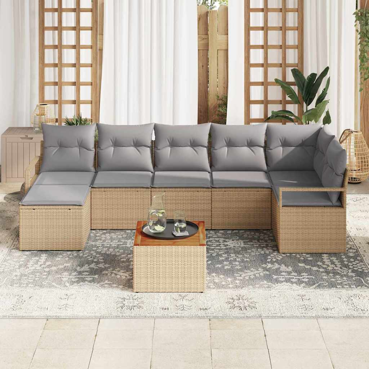 Outdoor-Sofa aus Korbgeflecht mit grauen Kissen. Davor steht ein kleiner Tisch mit Tablett und Getränken. Weiße Vorhänge und ein Teppich sind sichtbar.