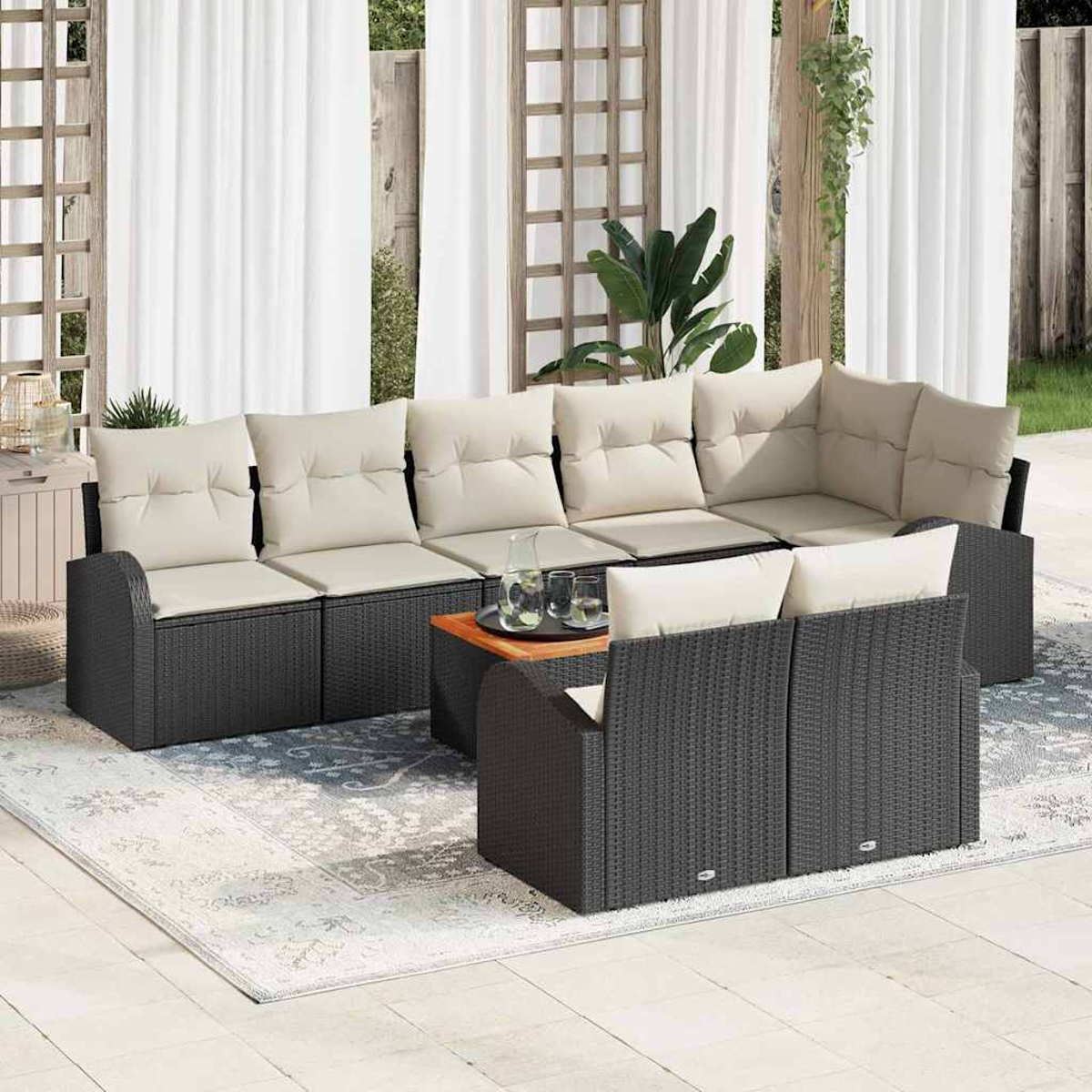 Outdoor-Sitzgruppe mit dunkelgrauen Korbmöbeln, beigen Kissen und einem Holztisch auf einem gemusterten Teppich.