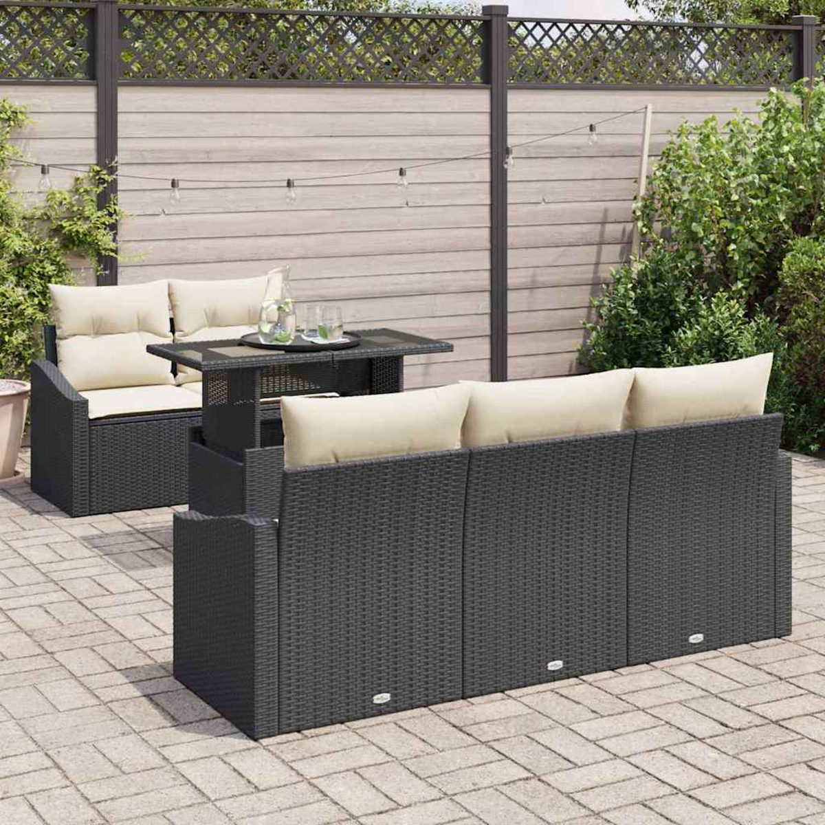 Outdoor-Möbelset: dunkelgraues Korbmöbel-Sofa und -Stuhl mit cremefarbenen Kissen, ein kleiner Tisch, in einer Gartenumgebung.