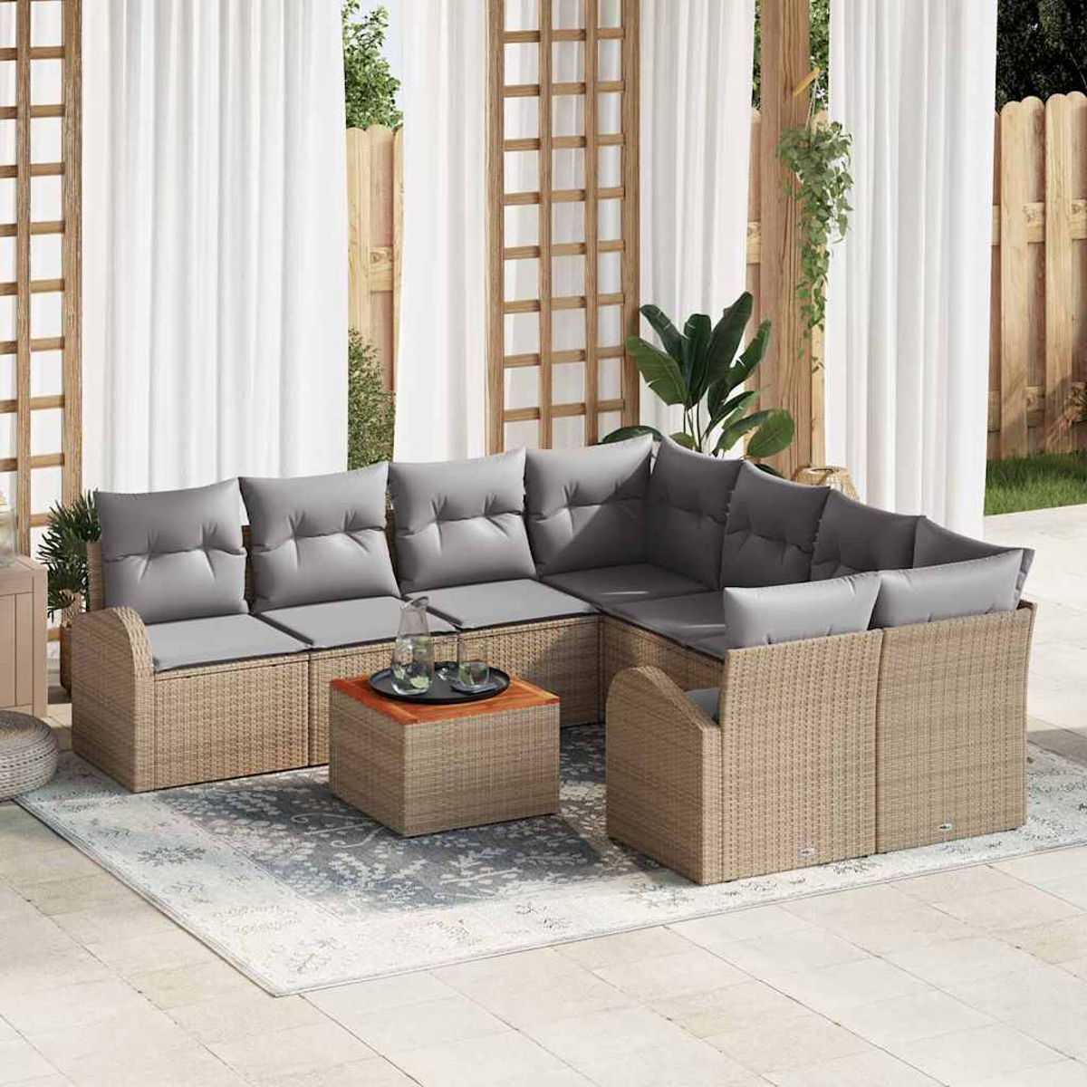 Garten-Sitzgruppe auf einer Terrasse. Sie hat gewebte braune Rahmen und graue Kissen. Davor stehen ein Couchtisch und ein Teppich.