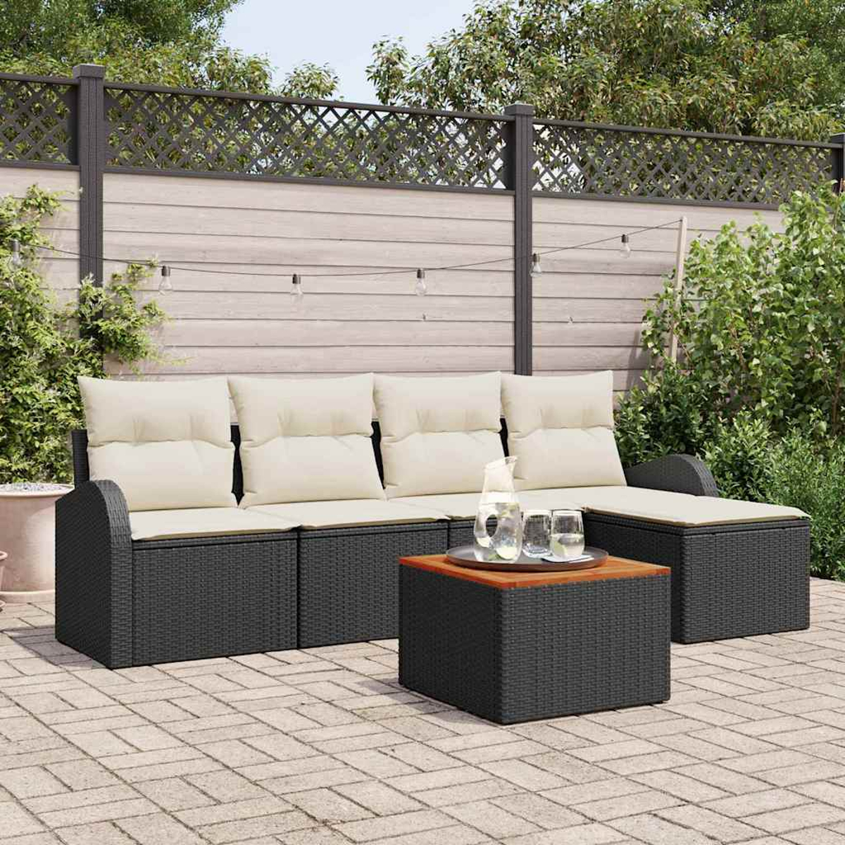 Gartenmöbel mit Couchtisch. Schwarzes Geflecht, beige Kissen und Holztisch. Hintergrund: Zaun und Pflanzen.